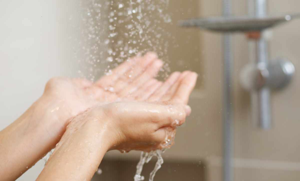 A woman uses hand to measure the water temperature